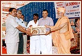 Pujya Siddeshwar Swami presents a school name plaque to one of the principals