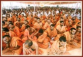 A large makeshift canopy hall provides shelter to sadhus and devotees engaged in chorusing and clapping to a bhajan 