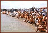 Sadhus and devotees avidly engaged in darshan by the river bank