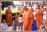 Swamishri offers a peacock feather to the child