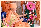 Swamishri places the sanctified garland around the balak's neck and pleases him 