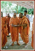 Swamishri writes a letter while standing along the way