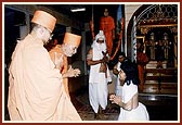 Swamishri bows when welcomed by a balak dressed as a sage