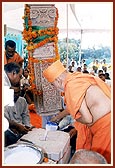 Swamishri performs pujan of pillar and fills the pillar base with cement