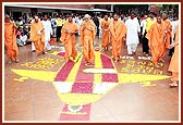 Swamishri walks on a floral design while on his way for Thakorji's darshan 