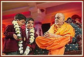 Swamishri garlands two young school children