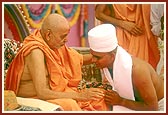Swamishri initiates a youth into parshad diksha and imparts the guru mantra