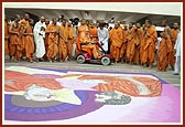Swamishri observes the rangoli of Yogiji Maharaj and himself done by a youth before the Yogi Smruti Mandir