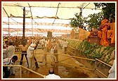 Swamishri begins the traditional spraying of water on devotee as they file pass 