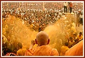 The crowd joyously moves forward to be drenched with the colored, holy water by Swamishri