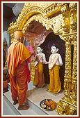 Holding a mirror before Shri Akshar Purushottam Maharaj