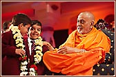 Swamishri garlands two young schoolchildren