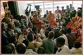 Swamishri seated amongst devotees at Terminal 3 listening to Viveksagar Swami