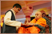 Swamishri blesses a balaks kirtan book by signing it