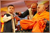 Swamishri asks the child to play the mini violin