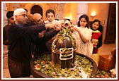 Devotees offering their devotion by performing abhishek of the Shivaling with milk and bilipatras