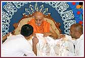  Swamishri closely looks at a shawl presented to him embroidered with the 64 characteristics of a true saint 