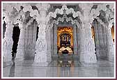 Shri Akshar Purushottam Maharaj seen through archways and columns beneath a magnificent central dome