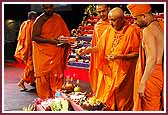 Swamishri throws flowers on the annakut offering and sanctifies the food items 