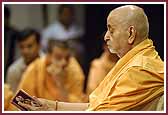 Swamishri carefully reads verses from the Shikshapatri