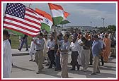 Devotees carry flags of India and USA in the Nagar Yatra 