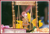Lord Harikrishna Maharaj graces a decorative swing during Swamishri's morning pooja