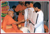 Swamishri accepting a devotional card prepared by balaks