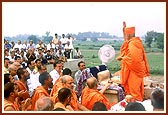 Swamishri blesses the devotees and sadhus by showering rice grains