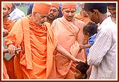 During his visit to the proposed land for a mandir Swamishri blesses an employee and his children who look after the proposed land for a new mandir