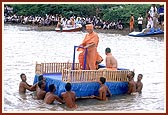 With Swamishri standing, the raft is pulled towards the main festival stage